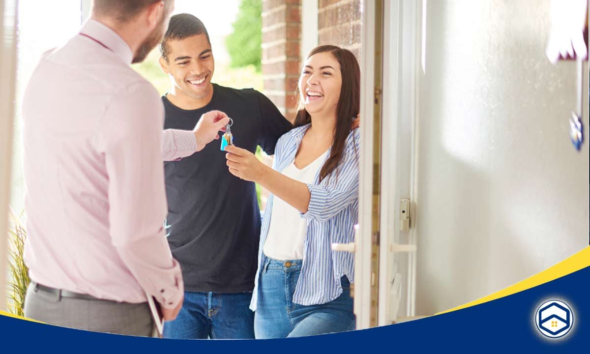 A happy couple receives house keys from a real estate agent, celebrating their new home.