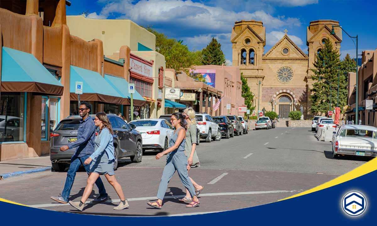 A vibrant scene of Downtown Santa Fe, featuring pedestrians walking past adobe-style buildings.