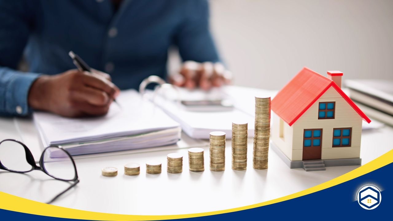 A person working at a desk with stacked coins and a miniature house, representing affordable housing and rent trends in Conroe - Conroe insurance providers for apartments.