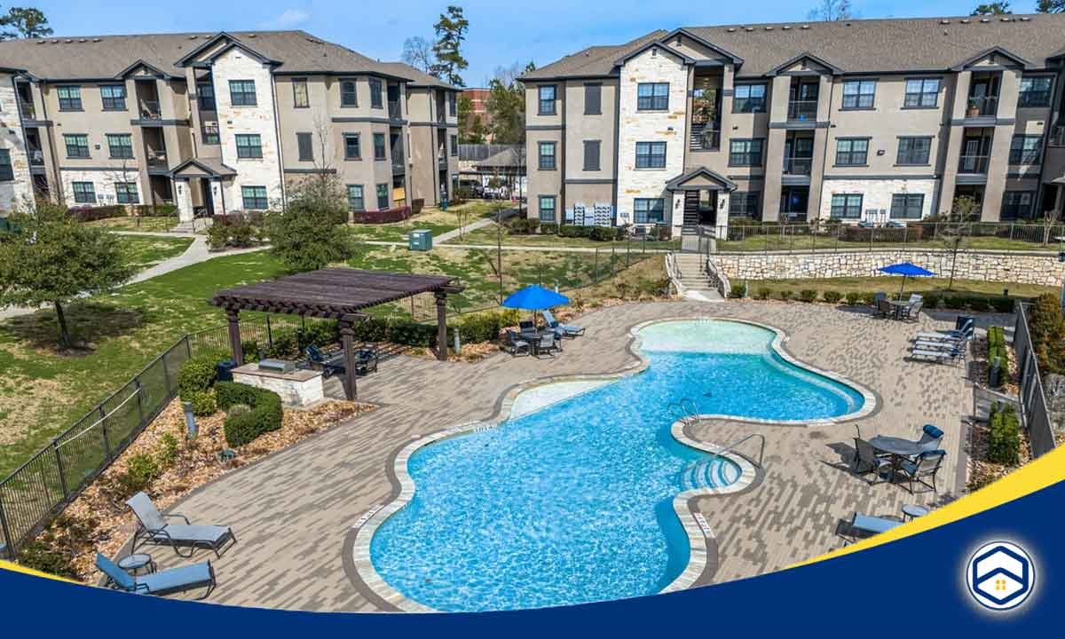 The image shows the West Creek Apartments, one of the top Conroe apartments offering video walkthroughs, with a swimming pool and other amenities.