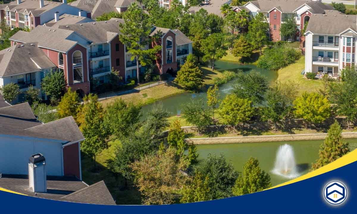 The image shows the Sunpark Apartment Homes, one of the top Conroe apartments offering video walkthroughs, with a scenic view of the community's amenities including a pond with a fountain.