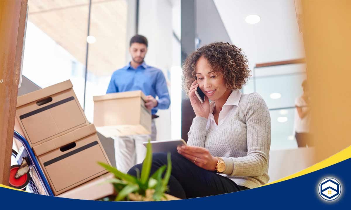 The image shows a woman talking on the phone while surrounded by moving boxes, indicating that she is in the process of planning her move to Conroe.