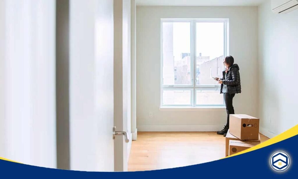 The image shows an empty apartment room with a person looking out the window, which could be relevant to the topic of "Houston low credit apartments".