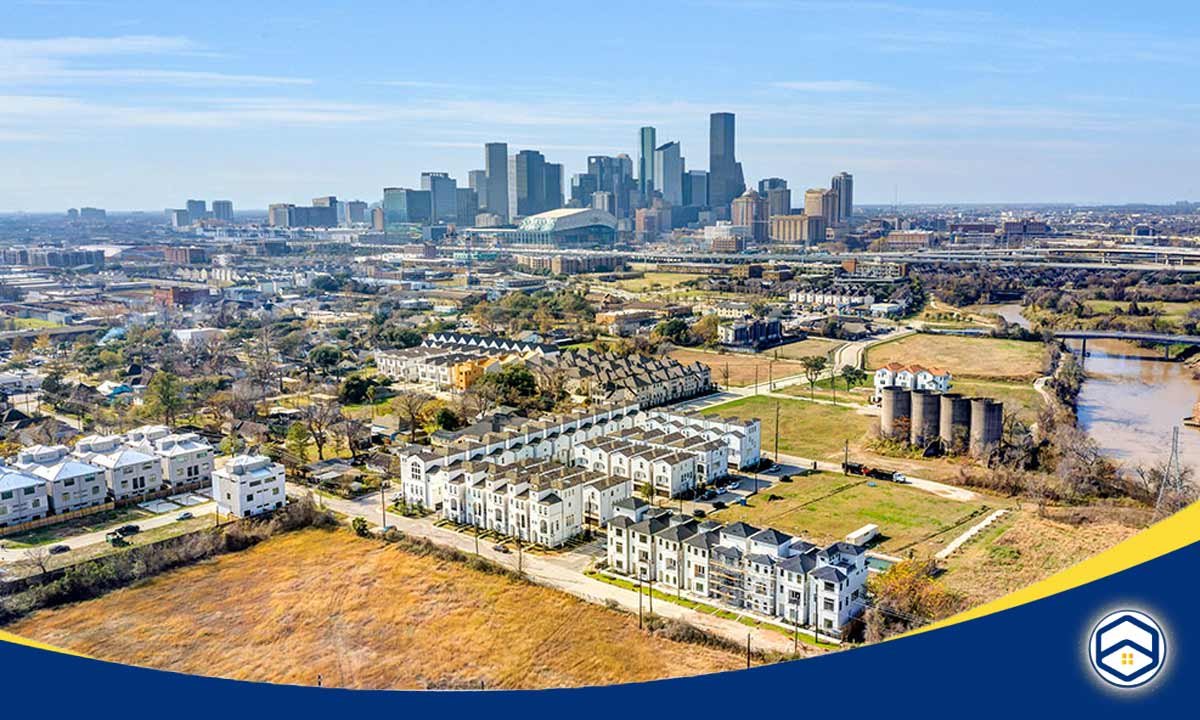 The image appears to show an aerial view of the East End neighborhood in Houston, Texas. The image depicts a mix of residential and commercial buildings, with the downtown Houston skyline visible in the background.