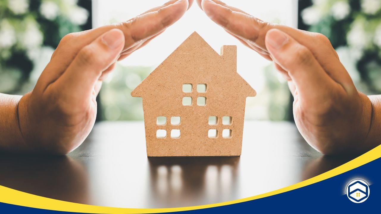 Hands forming a protective gesture over a small wooden house model, symbolizing cost-effective belongings insurance.