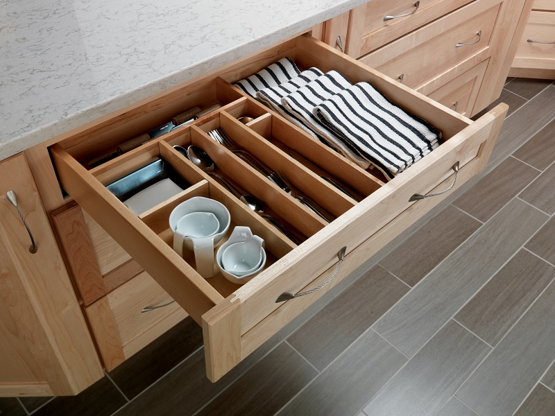 A deep kitchen drawer with dividers neatly organizing utensils, lids, and small kitchen gadgets for easy access and tidiness.